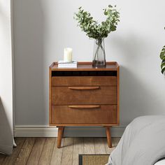 a bedroom with a bed, nightstand and potted plant on the side table next to it