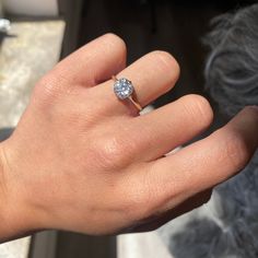 a woman's hand with a diamond ring on top of her left hand,