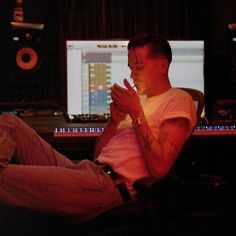 a man sitting in front of a computer screen with his hands clasped to his chest