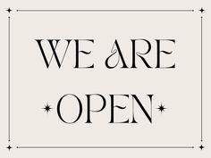 we are open sign in black and white with stars on the bottom, against a light gray background