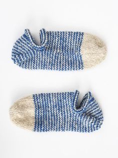 two pairs of blue and white knitted slippers on a white surface with one pair missing