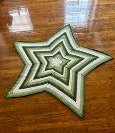 a green and white star shaped rug sitting on top of a wooden floor