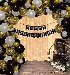 a happy anniversary balloon arch with black, white and gold balloons