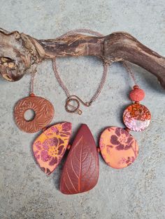 a necklace with five different colored stones and a brown leaf on it's chain