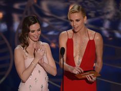 two women standing next to each other in front of a microphone and one holding an award