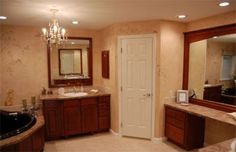 a large bathroom with marble counter tops and wooden cabinets, along with a chandelier hanging from the ceiling