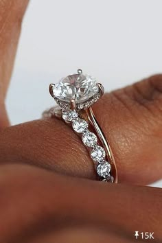 a woman's hand with a diamond ring on her finger and the other hand holding it