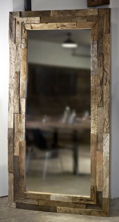 a mirror sitting on top of a wooden table next to a wall mounted light fixture