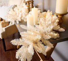 a white christmas tree with lit candles on a table