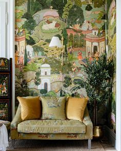 a green couch sitting in front of a painting on the wall next to a potted plant