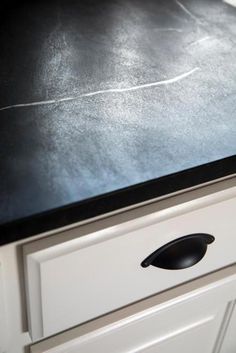 a black counter top sitting on top of a white cabinet