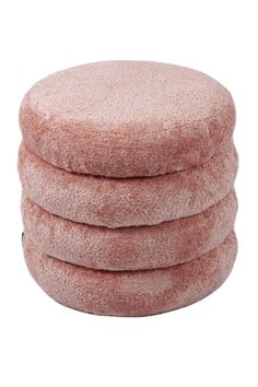 four pink round cushions stacked on top of each other in front of a white background