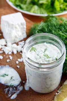 a jar filled with white sauce sitting on top of a wooden cutting board