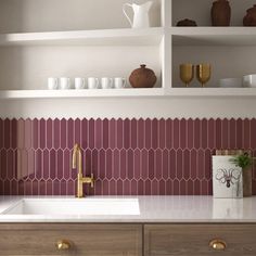 a kitchen with white cabinets and pink tile backsplashing, gold faucet