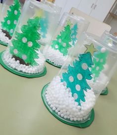 four plastic cups with christmas trees in them on a counter top, one is green and the other is white