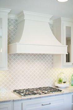 a stove top oven sitting inside of a kitchen next to white cabinets and counter tops