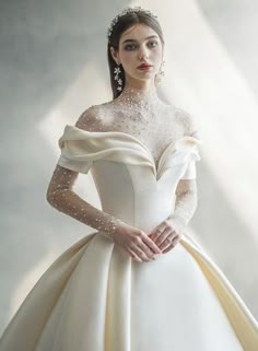 a woman in a white wedding dress with pearls on her head and shoulders, posing for the camera