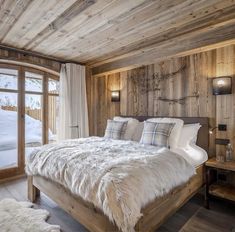 a large bed in a bedroom next to a window with snow on the outside wall