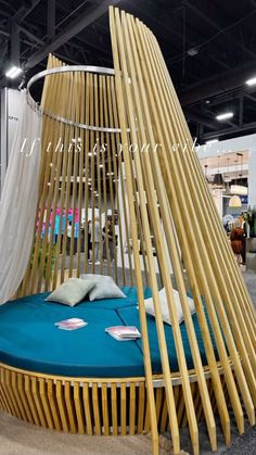 a bed made out of bamboo sticks with blue sheets and pillows on the bottom floor