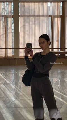 a woman taking a selfie with her cell phone in the middle of an empty room