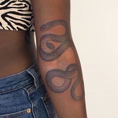 a woman's arm with a snake tattoo on the left side of her body