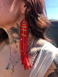 a woman with tattoos on her chest wearing red tassels and cross pendants