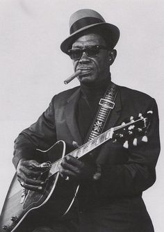 a man in a suit and hat playing a guitar