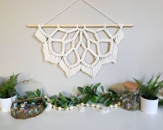 there is a macrame pattern hanging on the wall next to some potted plants