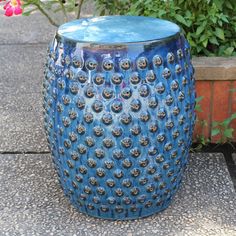 a blue vase sitting on top of a sidewalk next to a potted planter