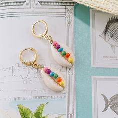 two pairs of earrings with colorful beads hanging from them on top of a piece of paper