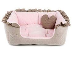 a dog bed with a heart shaped pillow on the side and a stuffed animal in it