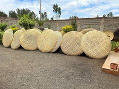 several large round wicker baskets lined up on the ground in front of a brick wall