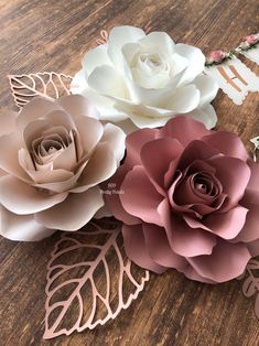 three paper flowers sitting on top of a wooden table