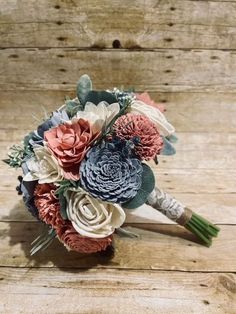 the bridal bouquet is made up of paper flowers and greenery, along with foliage