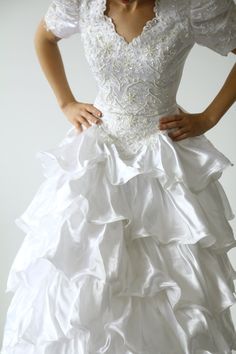 a woman in a white wedding dress with ruffles on the skirt and sleeves