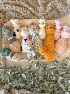 small crocheted animals sitting on top of a wooden tray next to eucalyptus branches