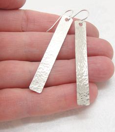 These are lightweight long hammered rectangle bar earrings in sterling silver, handmade by me. They have a rippled surface and a geometric feel. I polished them up to a shimmery shine. These hammered earrings are getting to be on the long side at 2-1/4 inches (5.9 cm) long. These can be ordered with sterling french hook earwires or sterling leverbacks. You can choose which during the checkout process. Thanks for reading this! I'm available to answer questions if you have any! Modern Hammered Linear Earrings For Gift, Modern Hammered Linear Earrings As Gift, Hammered Rectangular Sterling Silver Jewelry, Hammered Sterling Silver Jewelry In Rectangular Shape, Rectangular Hammered Sterling Silver Jewelry, Blue Sea Glass Necklace, Laser Engraved Gifts, Aromatherapy Gifts, Hammered Earrings