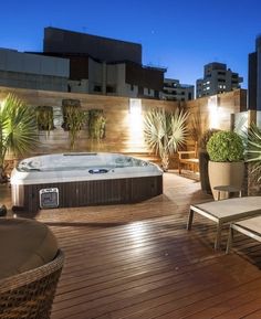 a hot tub sitting on top of a wooden deck next to a planter filled with potted plants