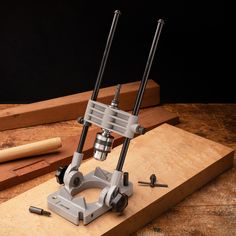 a machine that is sitting on top of a piece of wood next to some screws