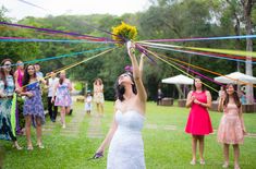 a woman in a white dress holds up a bunch of streamers as others look on