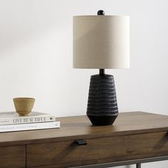 a table lamp sitting on top of a wooden dresser next to a bookshelf