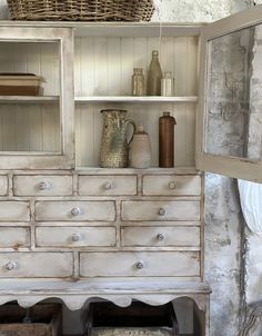 an old white dresser with drawers and baskets on top