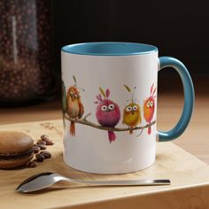 three colorful birds sitting on a branch next to a spoon and coffee cup with beans in the background