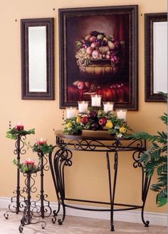 a table with flowers and candles on it in front of two framed pictures hanging on the wall