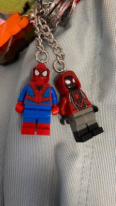 two lego spiderman keychains sitting on top of a bed