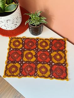 a crocheted placemat sits on a table next to a potted plant