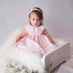 "Pink dress is made out of very soft, smooth Marchiano fabric. The neckline of the dress is finished with a beautiful lace in white. At the back of the dress a bow is attached made of the double-sided satin ribbon. The lining in the dress is made out of the cotton batiste, thanks to which it does not irritate the child's skin. The bottom of the dress is finished with guipure and double-sided satin belt. The model has an invisible zipper. The dress is available in four colour options: WHITE, BLUE White Bow Dress For First Birthday, White Dress With Bow For First Birthday, Princess-style Baptism Dress With Bow, First Birthday Dress With Lace And Ruffles, First Birthday Lace Dress With Ruffles, Princess Dress With Lace Bodice For Baptism, Lace Ruffle Dress For First Birthday, Pink Lace Bodice Dress For Baptism, Sleeveless Princess Dress With Lace Trim For Baptism