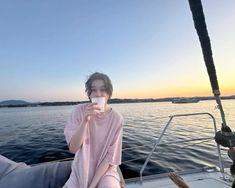 a woman sitting on the back of a boat drinking from a cup in front of her