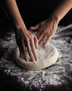 a person kneading dough on top of a floured surface with their hands