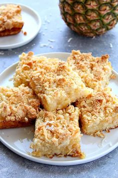 several pieces of food on a plate next to a pineapple and another piece of cake